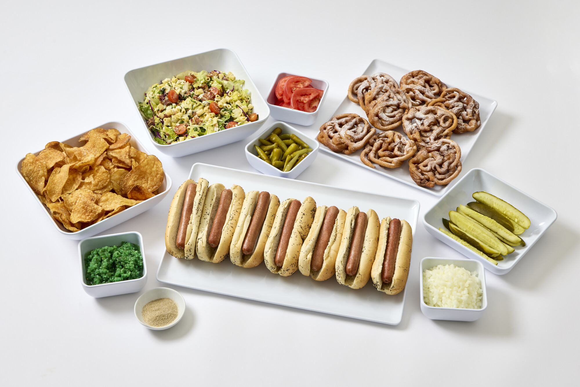 Paramount Events' 2026 Chicago baseball season dropoff catering spread featuring chicago style hot dogs, pickle spears, Chicago chopped salads, house made potato chips, and funnel cakes